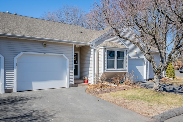 ranch-style house with driveway, roof with shingles, and an attached garage