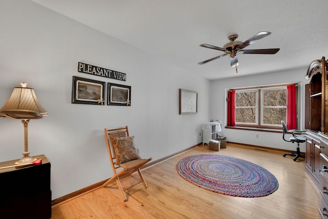 sitting room with a ceiling fan, wood finished floors, and baseboards