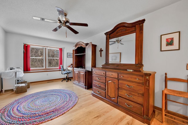 bedroom featuring baseboards, light wood-style flooring, a textured ceiling, and ceiling fan