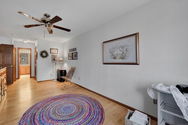 sitting room with baseboards, light wood-type flooring, and ceiling fan