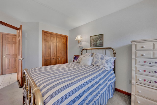 bedroom with a closet, light colored carpet, and baseboards