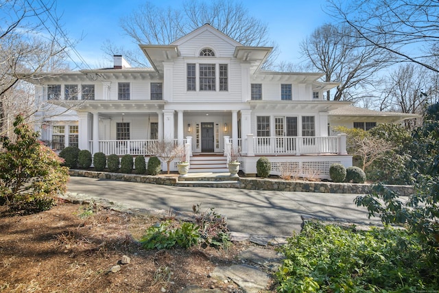 italianate-style house featuring covered porch and a chimney