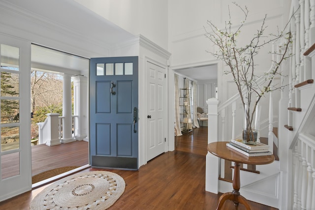 entrance foyer featuring stairway, a high ceiling, ornate columns, and dark wood-style flooring