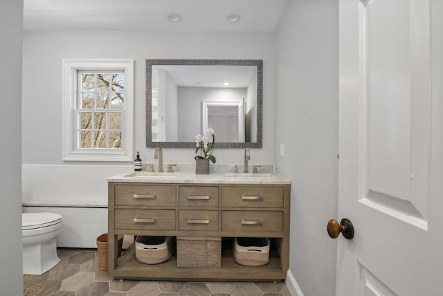 full bath featuring a sink, toilet, and double vanity