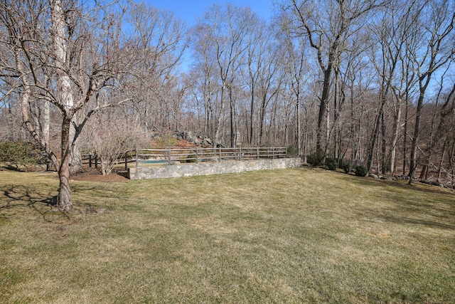 view of yard with a forest view and fence