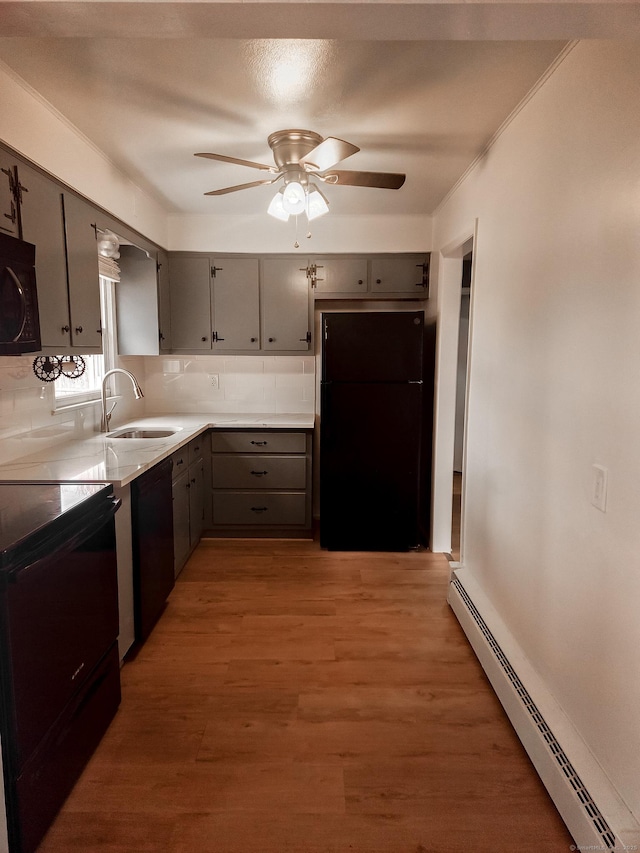 kitchen with black appliances, gray cabinetry, a baseboard heating unit, tasteful backsplash, and light wood finished floors