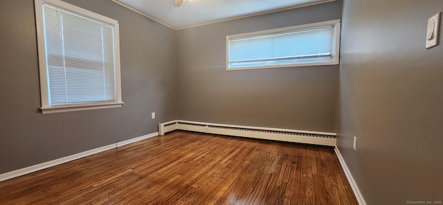 empty room featuring a baseboard radiator, baseboards, and wood finished floors