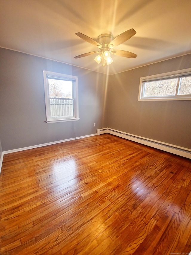 unfurnished room featuring hardwood / wood-style flooring, a ceiling fan, baseboards, and a baseboard radiator