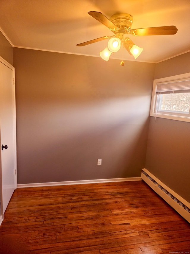 unfurnished room featuring ornamental molding, a ceiling fan, a baseboard heating unit, wood finished floors, and baseboards