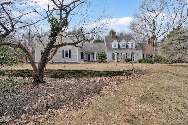 new england style home featuring a front yard and a chimney