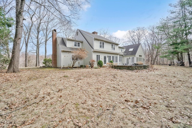 back of property with a wooden deck and a chimney