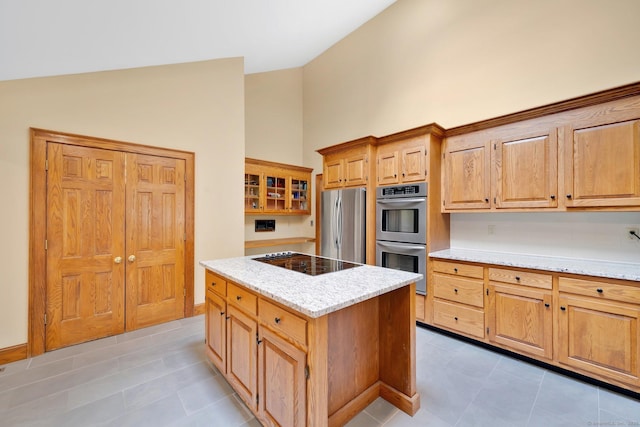 kitchen with high vaulted ceiling, light stone counters, a kitchen island, stainless steel appliances, and glass insert cabinets