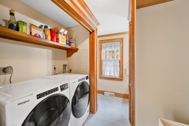 washroom featuring light tile patterned floors, laundry area, washer and dryer, and visible vents