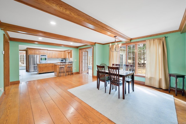 dining area featuring beamed ceiling, crown molding, light wood finished floors, baseboards, and a chandelier