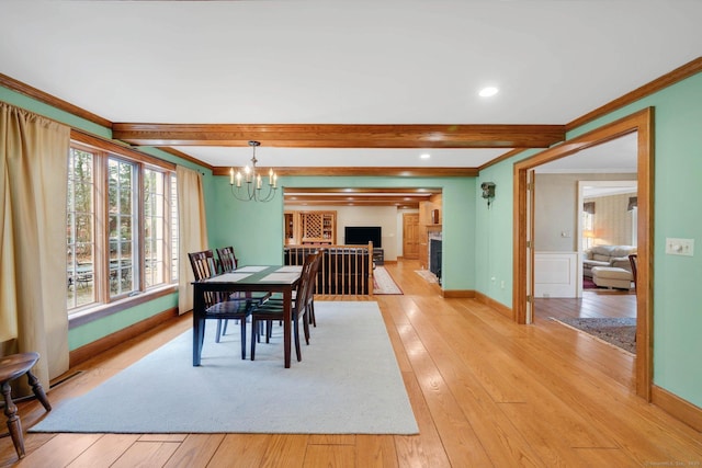 dining area with baseboards, beam ceiling, an inviting chandelier, light wood-style flooring, and ornamental molding