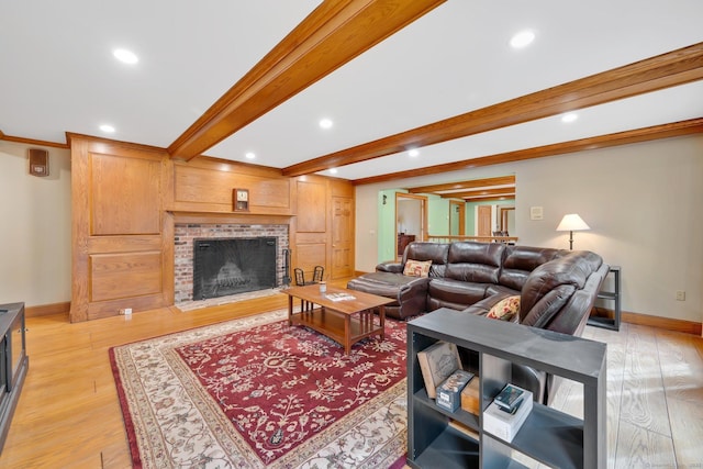 living area featuring beamed ceiling, a fireplace, baseboards, and light wood finished floors