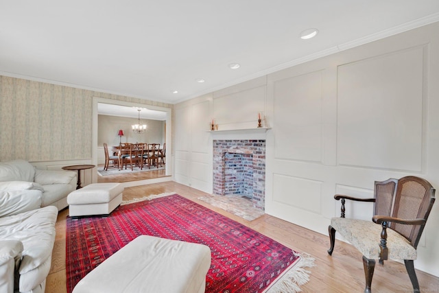 living area with crown molding, recessed lighting, an inviting chandelier, wood finished floors, and a decorative wall