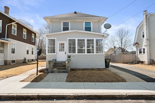 traditional style home featuring fence, roof with shingles, entry steps, and a sunroom