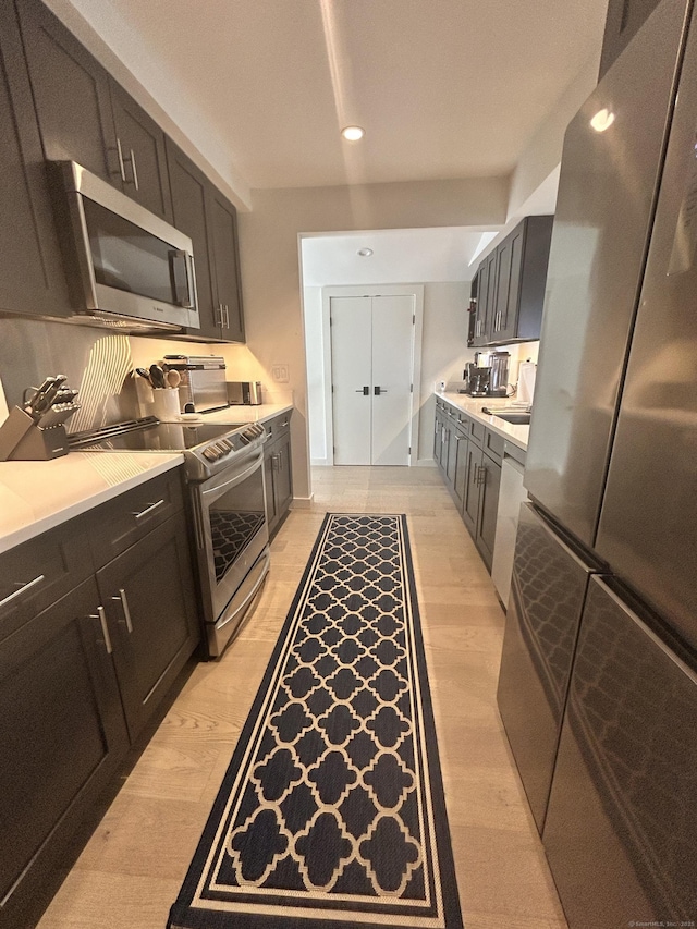 kitchen with light countertops, recessed lighting, light wood-style floors, stainless steel appliances, and a sink