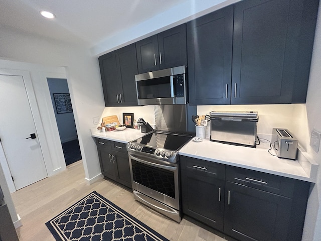 kitchen with dark cabinets, light wood finished floors, and stainless steel appliances