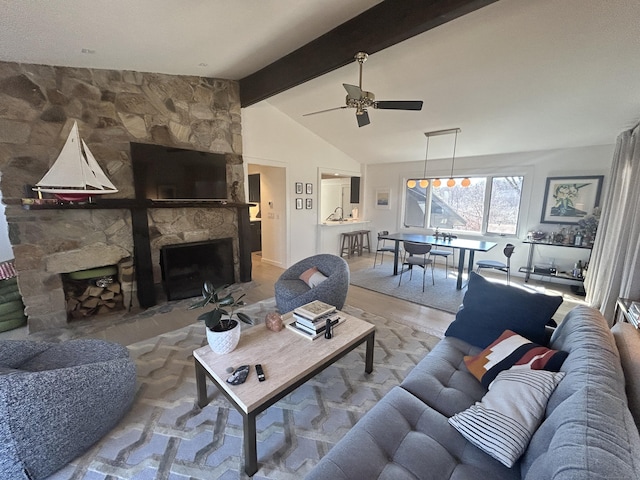 living area featuring lofted ceiling with beams, wood finished floors, ceiling fan, and a fireplace