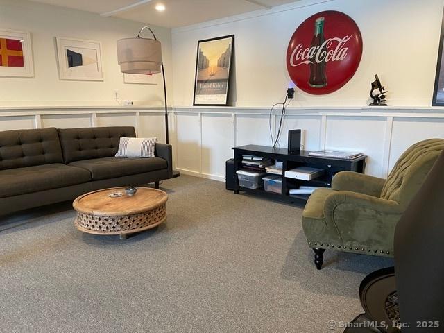 carpeted living room featuring a decorative wall, recessed lighting, and a wainscoted wall