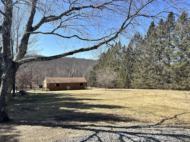 view of yard featuring a forest view and fence