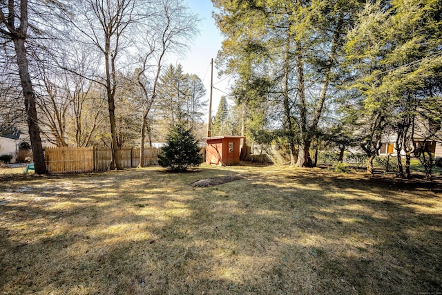 view of yard featuring a shed, an outdoor structure, and fence