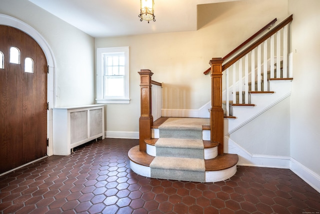 entryway featuring baseboards, arched walkways, and stairway