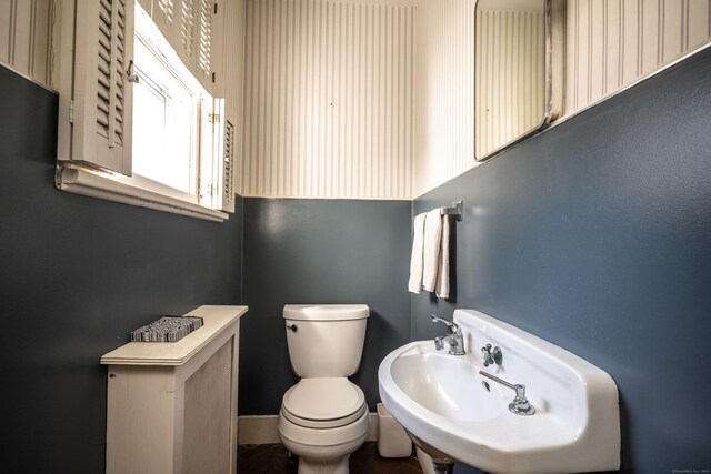 half bathroom featuring a sink, baseboards, and toilet