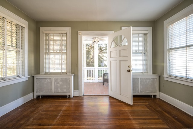 doorway to outside with dark wood finished floors, a healthy amount of sunlight, and baseboards