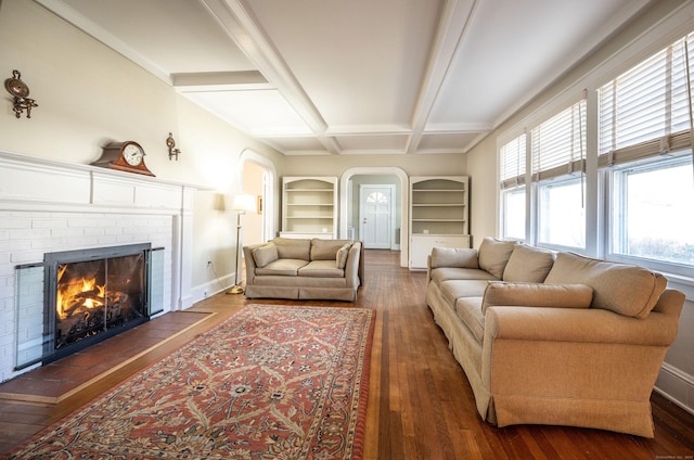 living room with built in shelves, wood finished floors, baseboards, coffered ceiling, and a brick fireplace