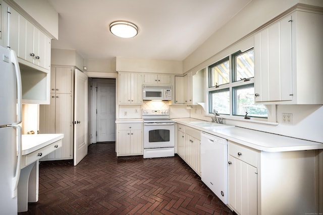 kitchen featuring white appliances, light countertops, brick floor, and a sink