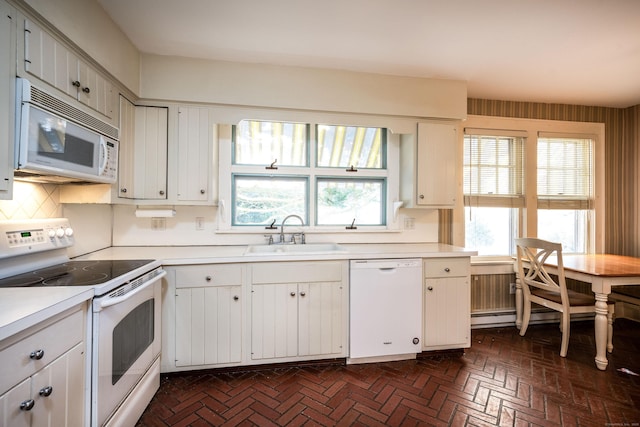 kitchen featuring white appliances, brick floor, a sink, light countertops, and white cabinetry