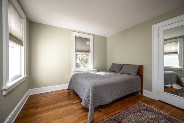 bedroom featuring multiple windows, baseboards, and hardwood / wood-style flooring