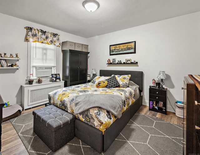 bedroom with radiator and wood finished floors