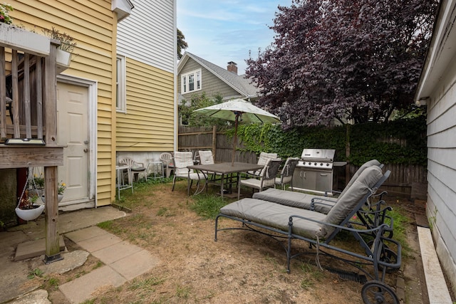 view of patio with grilling area, outdoor dining area, and fence