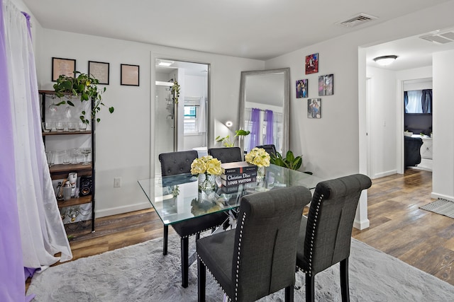 dining room featuring wood finished floors, visible vents, and baseboards