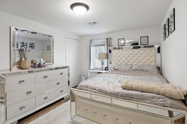 bedroom featuring wood finished floors, visible vents, and a closet