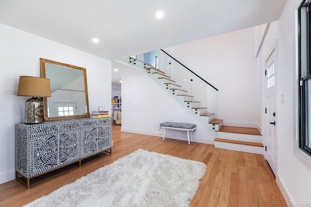 foyer featuring baseboards, recessed lighting, wood finished floors, and stairway
