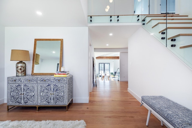 hall featuring baseboards, a high ceiling, wood finished floors, and stairs