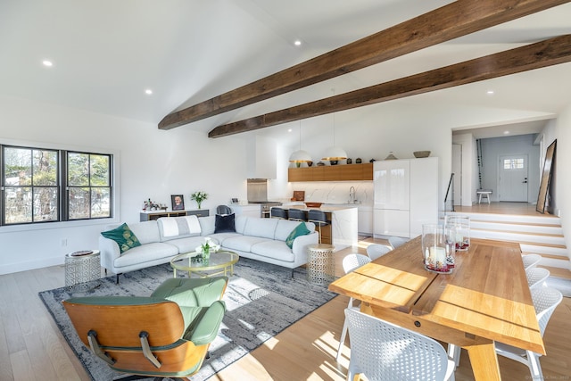 living area featuring recessed lighting, lofted ceiling with beams, light wood-style floors, and a wealth of natural light
