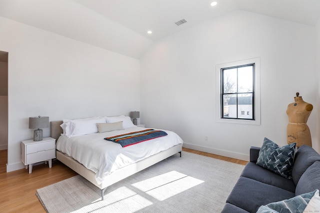 bedroom featuring baseboards, vaulted ceiling, visible vents, and light wood-style flooring