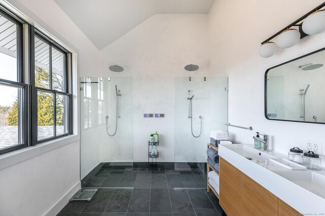 bathroom featuring vanity, lofted ceiling, tile patterned flooring, walk in shower, and baseboards
