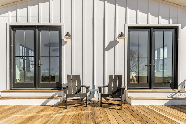 doorway to property with french doors, board and batten siding, and a wooden deck