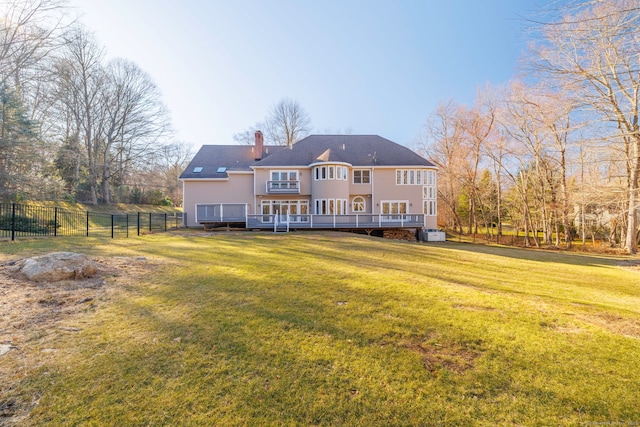 rear view of property featuring a wooden deck, a yard, fence, and a chimney