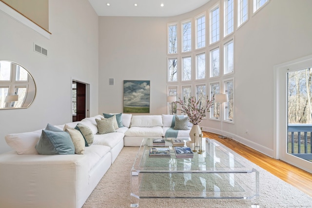 living area with a wealth of natural light, baseboards, wood finished floors, and recessed lighting