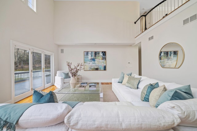 living room featuring visible vents, baseboards, a high ceiling, and wood finished floors