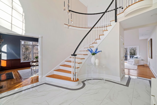 staircase featuring baseboards, marble finish floor, and a towering ceiling