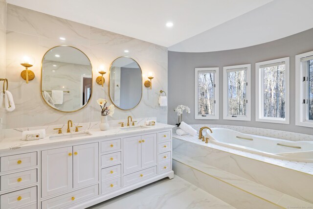 full bath with a sink, a garden tub, marble finish floor, and double vanity